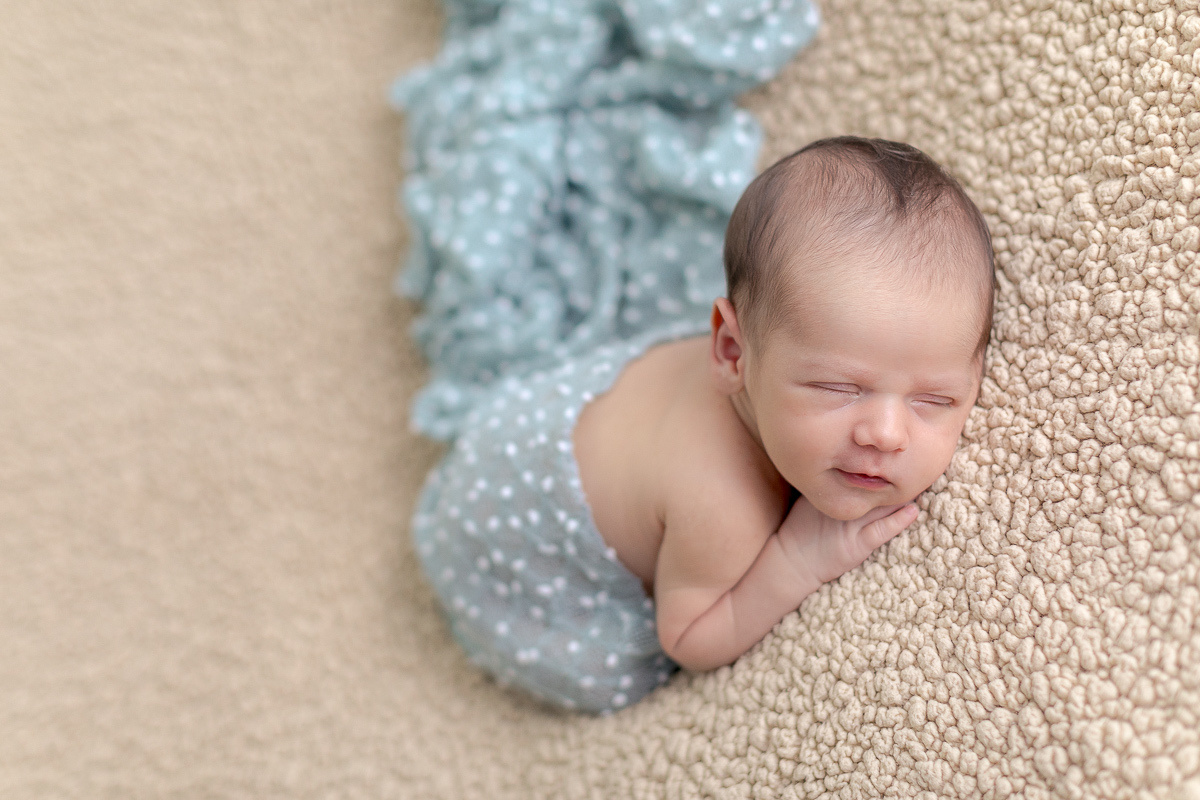 Foto feita no estúdio Gustavo Sousa Newborn em Curitiba. Pose básica no pufe. Manta bege e paninho azul pipoca.