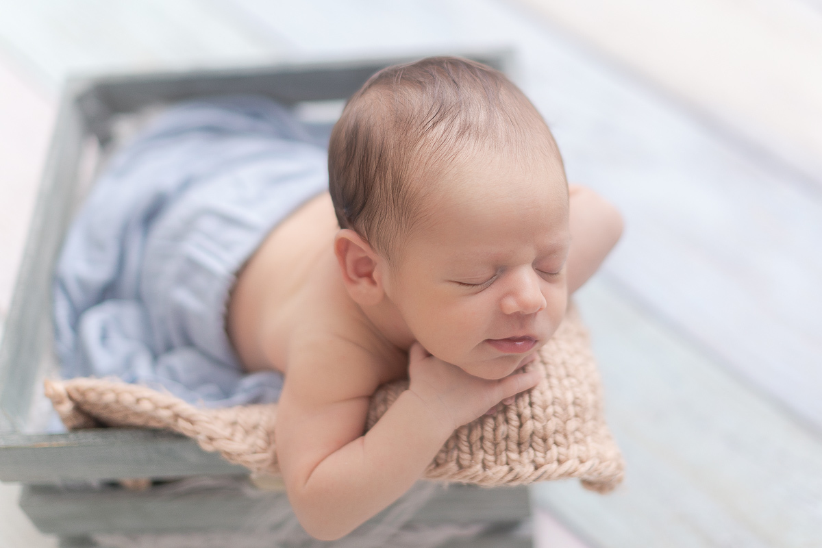 Foto feita no estúdio Gustavo Sousa Newborn em Curitiba. Pose do bracinho. Fundo fotográfico azul e beje.  Dentro do balde. Sorriso. 