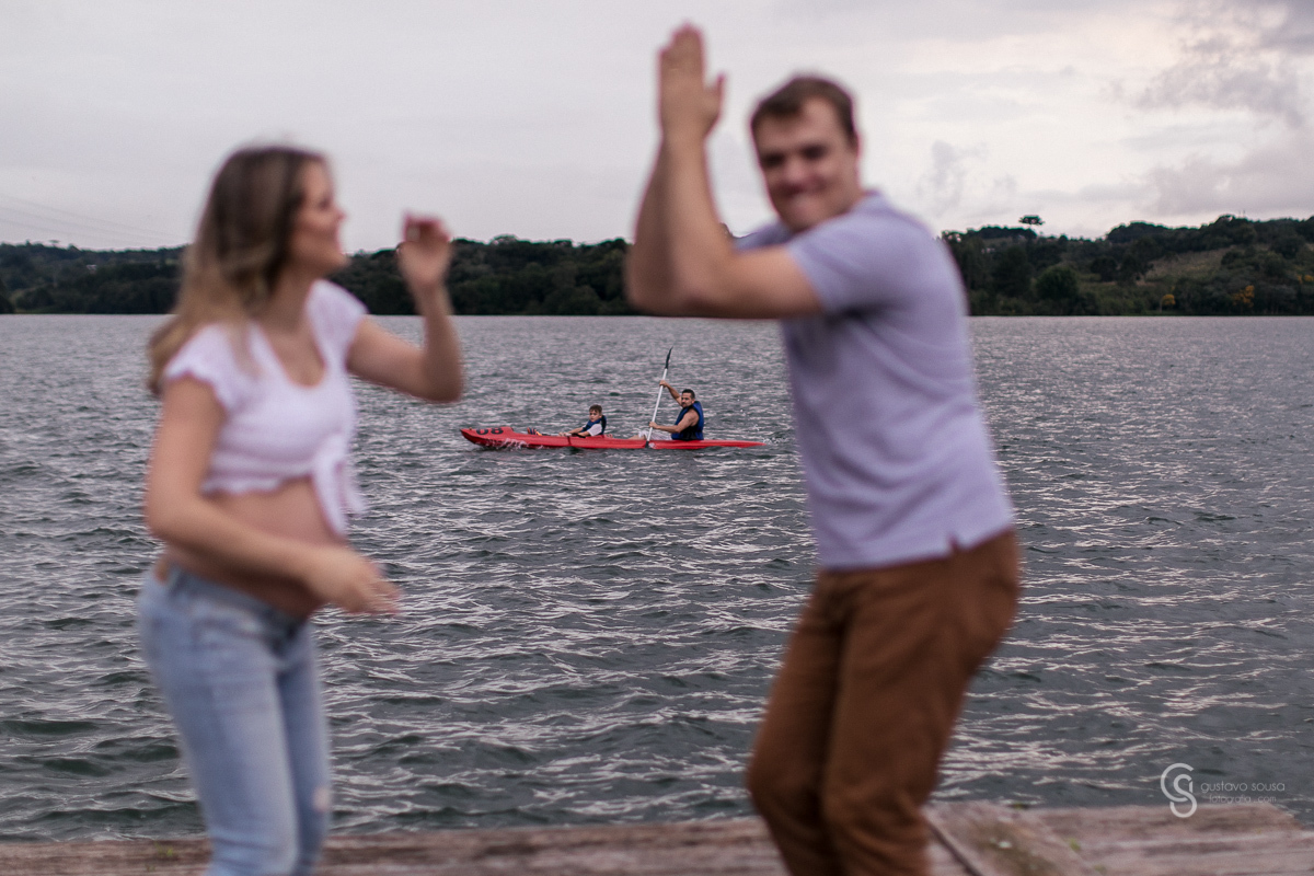 Ensaio gestante da Paty e Jo no estúdio Gustavo Sousa fotografia em Curitiba. Book em externa. Vestido florido Local Laggus Residencial Náutico Mãos na barriga . Gustavo Sousa Fotografia. Dança no deck de madeira. Canoa, barco, jangada, caiaque ao fundo.