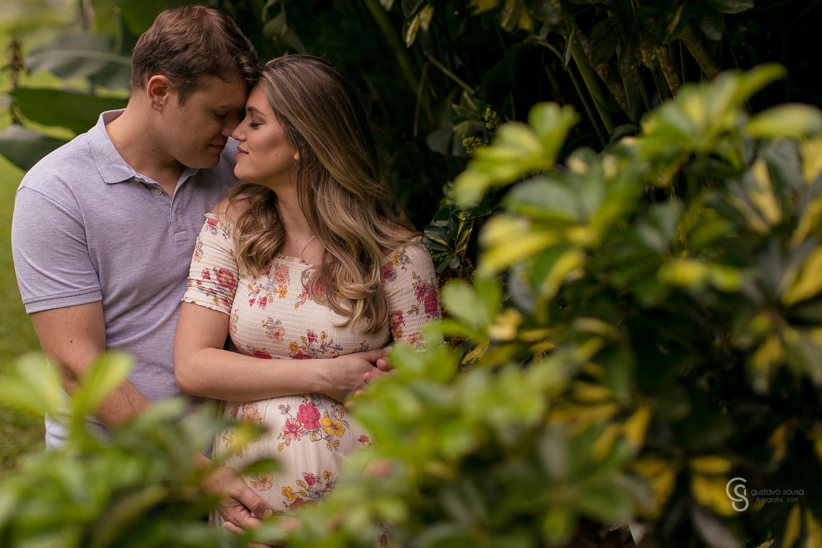 Ensaio gestante da Paty e Jo no estúdio Gustavo Sousa fotografia em Curitiba. Book em externa. Vestido florido. Vegetação verde. Local Laggus Residencial Náutico