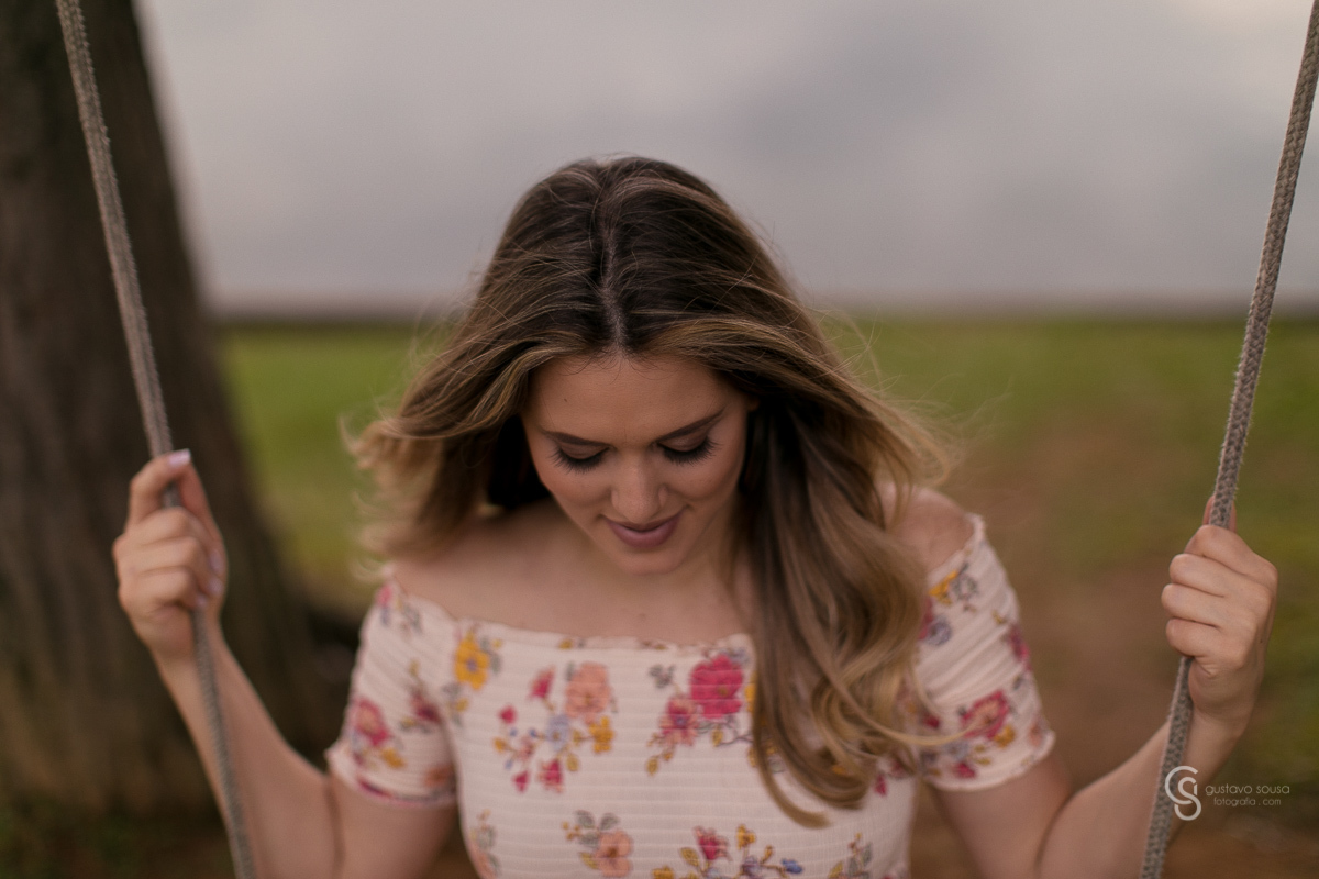 Ensaio gestante da Paty e Jo no estúdio Gustavo Sousa fotografia em Curitiba. Book em externa. Vestido florido Local Laggus Residencial Náutico Mãos na barriga . Gustavo Sousa Fotografia. No balanço.