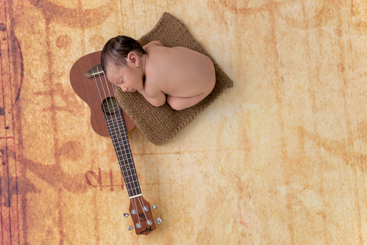 Ensaio Newborn do Leonardo feito nos estúdio Gustavo Sousa fotografia em Curitiba.  Foto feita cheia de amor, segurança e carinho. Fundo musical. Deitado no ukulele que é um instrumento musical havaiano