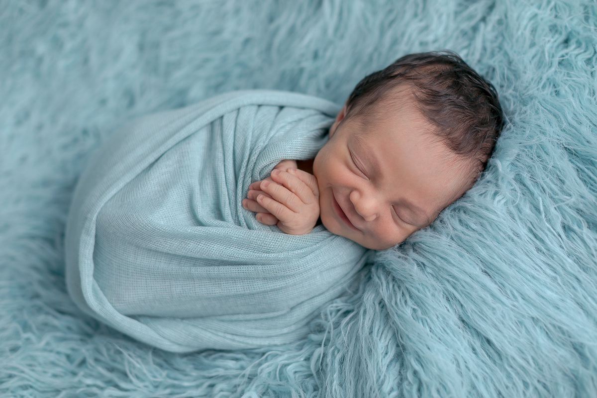 Ensaio Newborn do Leonardo feito nos estúdio Gustavo Sousa fotografia em Curitiba.  Foto feita cheia de amor, segurança e carinho. Fundo de pelo azul enrolado no paninho. Sono suave. Produção Clean. Sorriso.