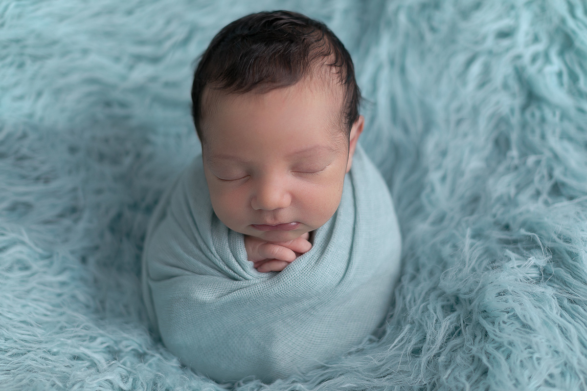 Ensaio Newborn do Leonardo feito nos estúdio Gustavo Sousa fotografia em Curitiba.  Foto feita cheia de amor, segurança e carinho. Fundo de pelo azul enrolado no paninho. Sono suave. Produção Clean. Pose saquinho de batatas.