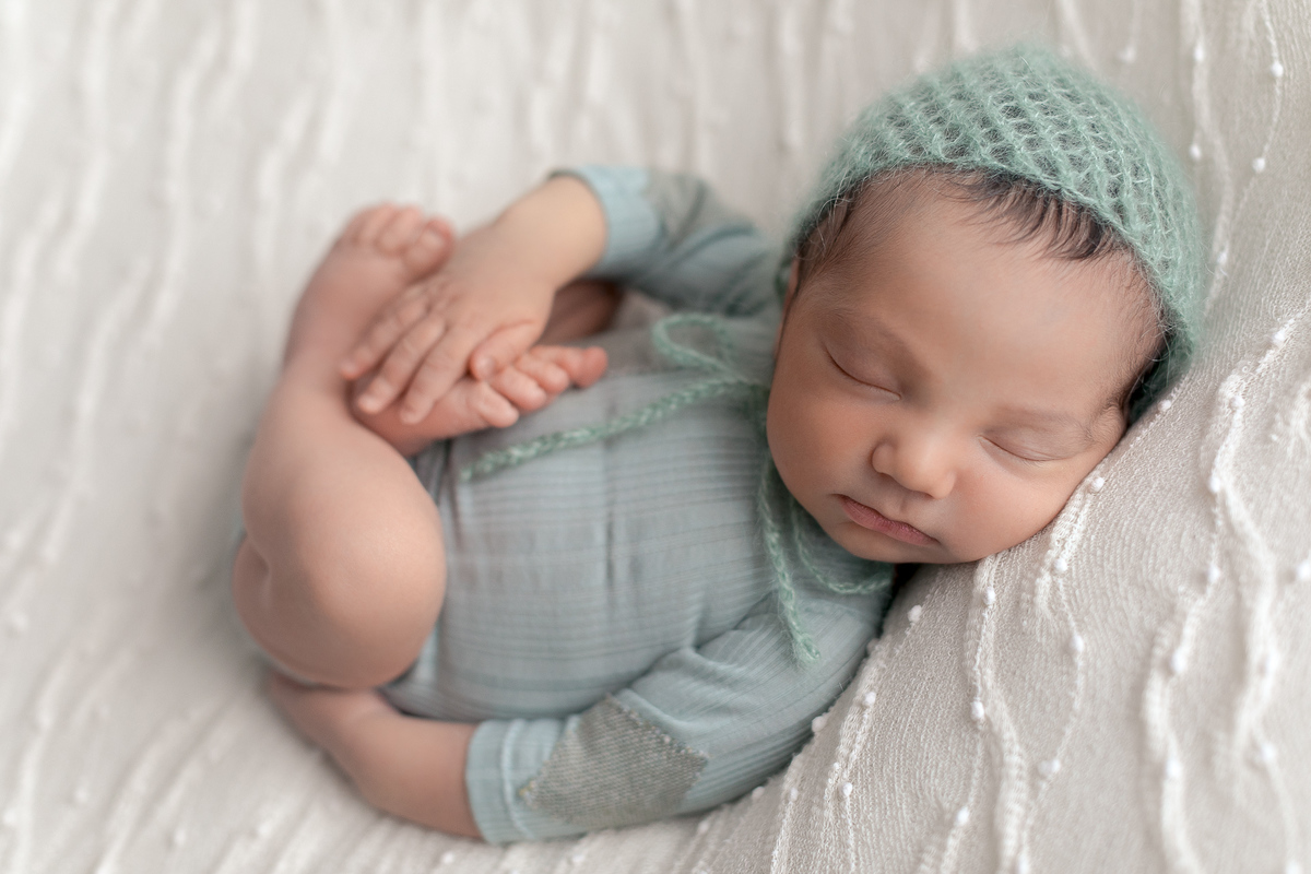Ensaio Newborn do Leonardo feito nos estúdio Gustavo Sousa fotografia em Curitiba.  Foto feita cheia de amor, segurança e carinho. O Leonardo está na pode de barriguinha para cima. Verde água. Produção Clean