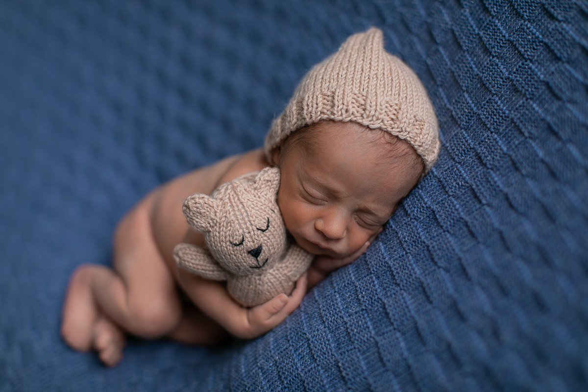 Ensaio Newborn do Pedro. Book feito no estúdio do Gustavo Sousa em Curitiba. Foto cleam, minimalista, simples, manta azul. Bebê dormindo segurando ursinho. Manta azul.