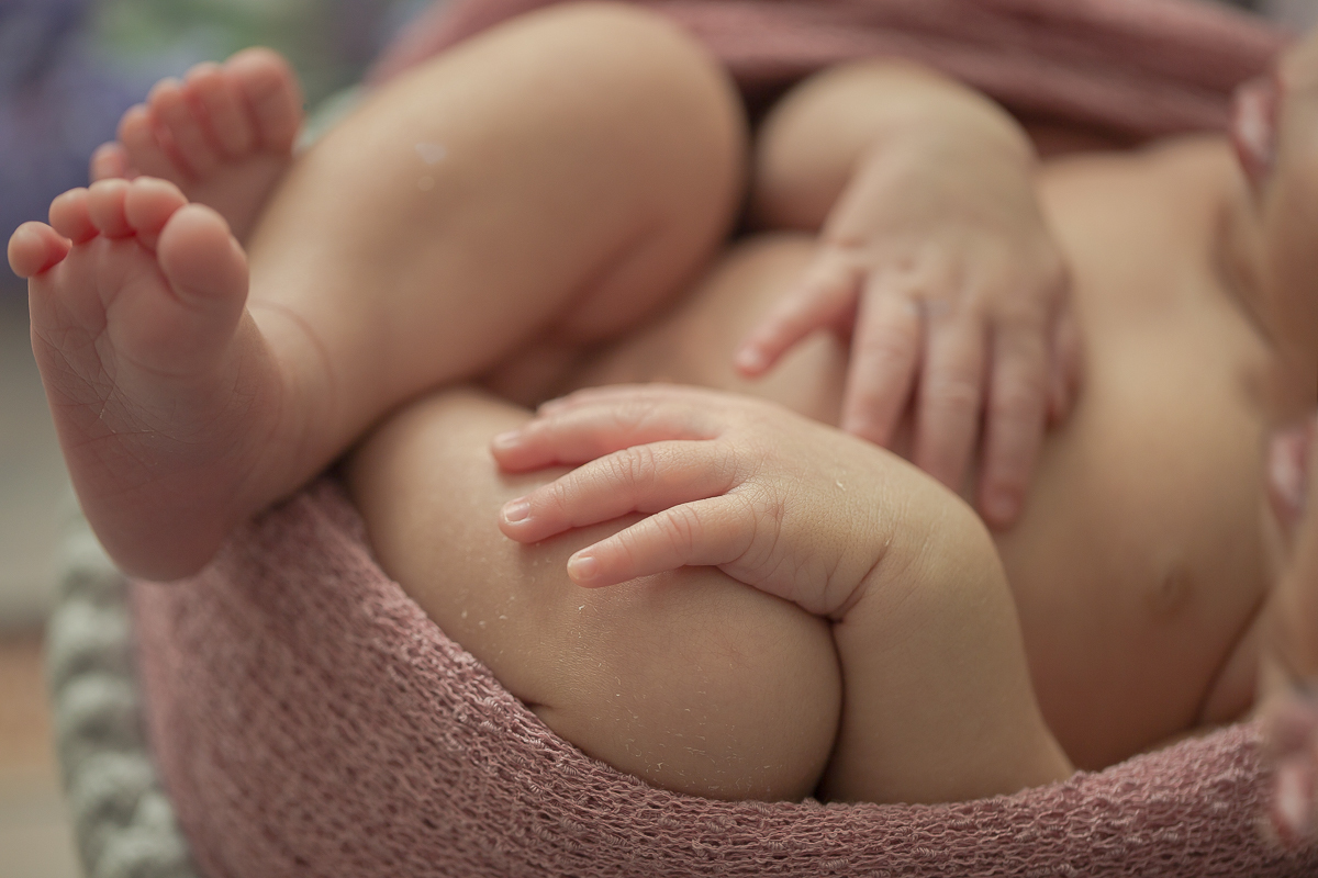 Ensaio newborn em Curitiba. Book feito  em produção cleam. Gustavo Sousa e Kátia Hille. Pose Básica. Fundo rosa. Manta Pipoca, roupa bege. Fundo de madeira. Pose de barriga para cima. Detalhe pś e mãos