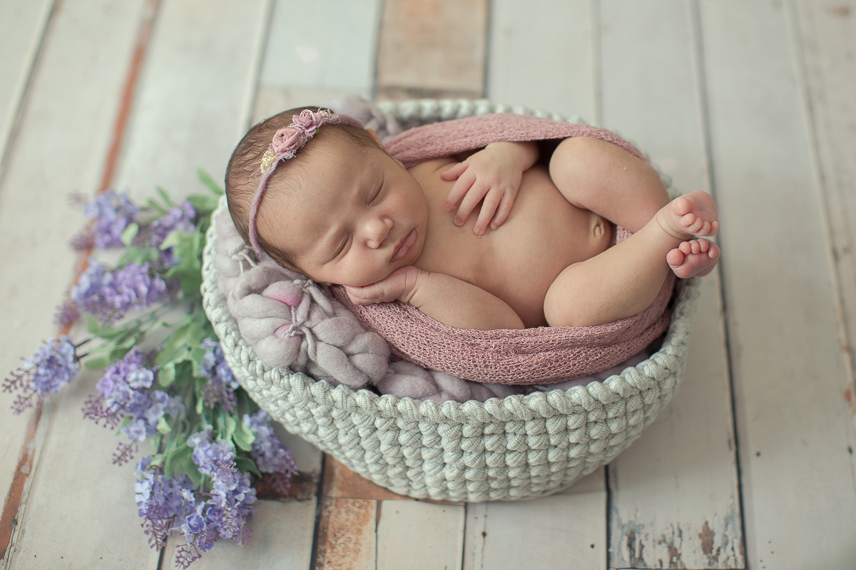Ensaio newborn em Curitiba. Book feito  em produção cleam. Gustavo Sousa e Kátia Hille. Pose Básica. Fundo rosa. Manta Pipoca, roupa bege. Fundo de madeira. Pose de barriga para cima. flores