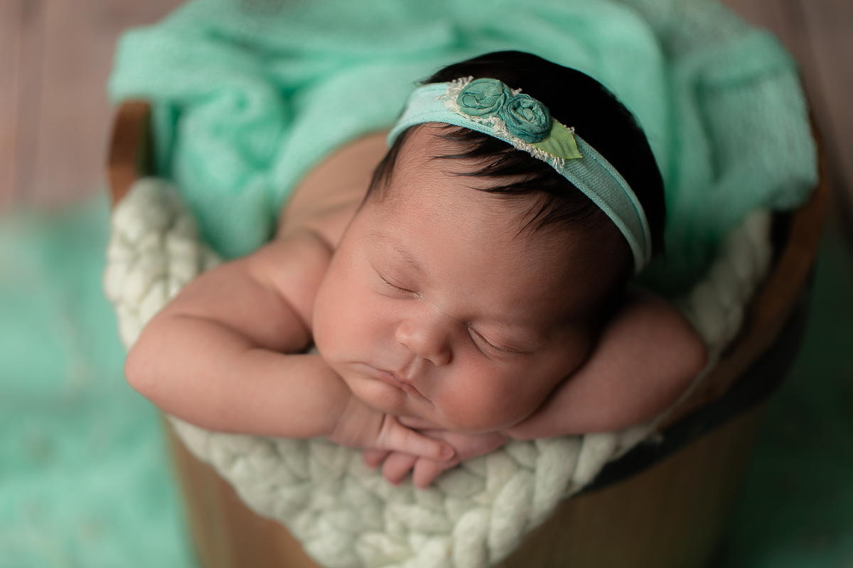 Ensaio Newborn da Maitê feita no estúdio Gustavo Sousa fotografia em Curitiba.  Foto feita cheia de amor, segurança e carinho. Produção simples e Clean feita pensado nela, no quartinho e nos papais. Fundo de madeira. No Balde de madeira. Tonalidade verde.