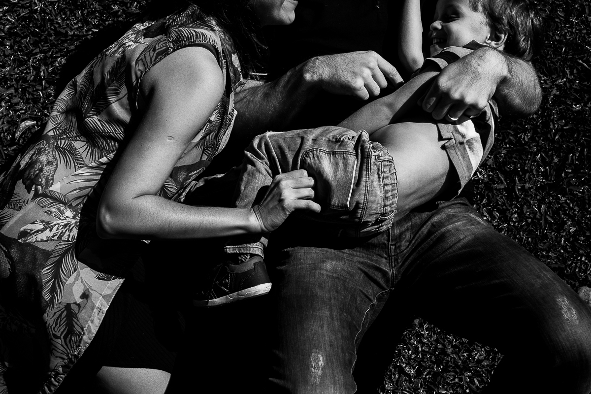 Gustavo Sousa fotografia em ensaio família e gestante na fazenda e haras perto de Curitiba. família brincando na grama deitados preto e branco