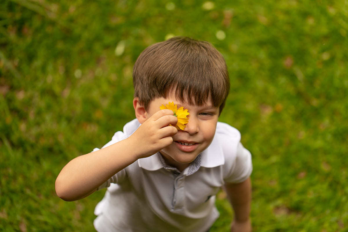 gustavo sousa fotografa na chácara Mangala em Curitiba. Fotos espontâneas. Ensaio gestante e família.  Criança brinca com a folha