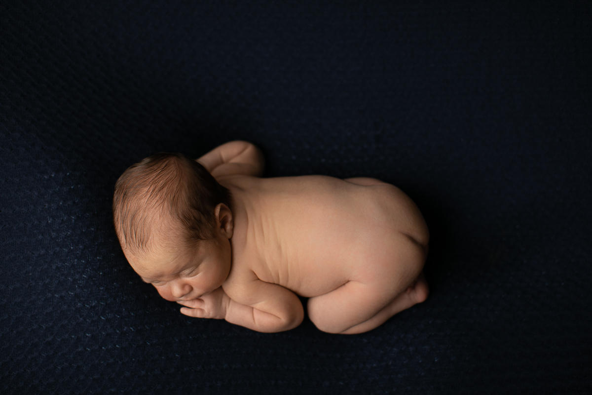 gustavo sousa fotografia faz ensaios e books de gestante e newborn em Curitiba e região. O Otávio foi fotografado em plena segurança e conforto. Muito amor foi dado aqui. Foto no puffe azul escuro. Angulo de cima.