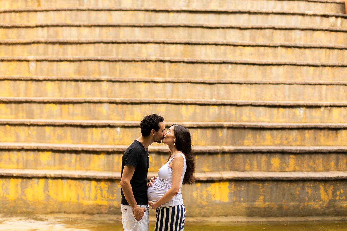 Gustavo Sousa fotografia de gestante. Book de grávida no Bosque do Alemão. linhas amarelas. Casal se beijando.