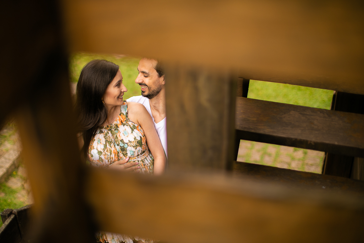 Gustavo Sousa fotografia de gestante. Book de grávida no Memorial Ucraniano. Vestido florido. Ele básico de branco. Nas escadas. 
