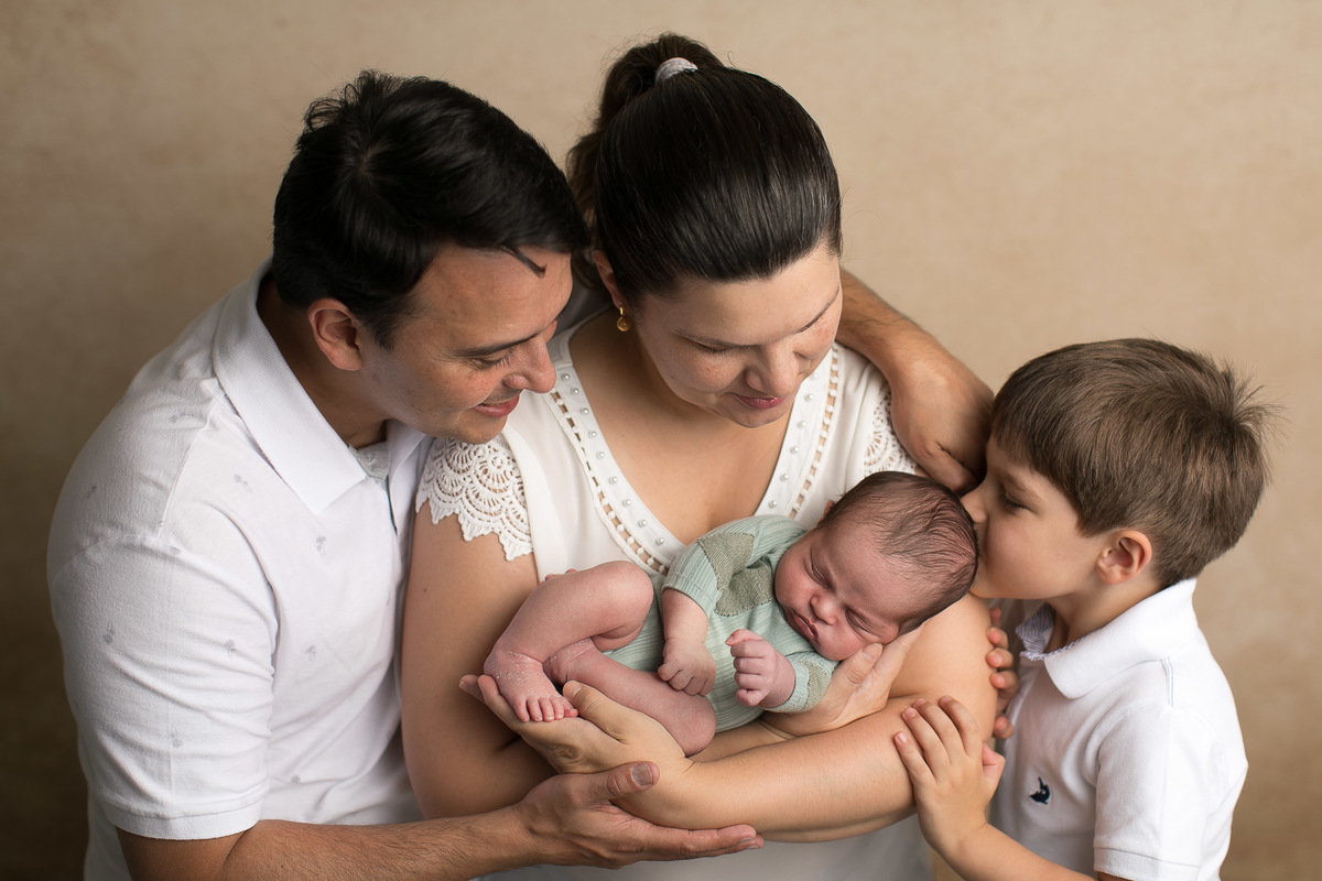Ensaio Newborn Gustavo Sousa Fotografia em Maringá. book com a família toda com beijo no bebê