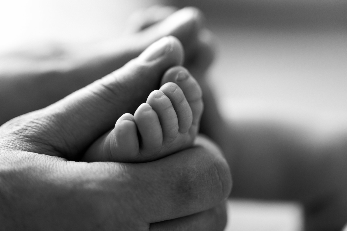 Gustavo Sousa estúdio de fotografia em Maringá-PR. Ensaio e book fotográfico newborn lifestyle e família. Foto de mãos segurando o pezinho do bebê.