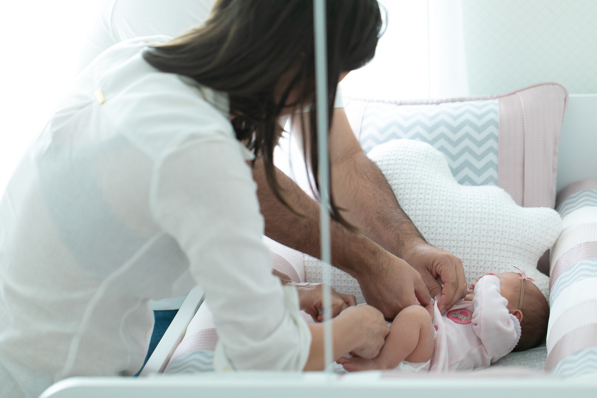 Gustavo Sousa estúdio de fotografia em Maringá-PR. Ensaio e book fotográfico newborn lifestyle e família. Foto em família, pai e mãe trocando a bebê.
