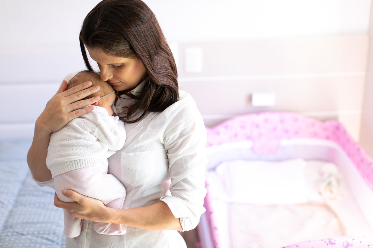 Gustavo Sousa estúdio de fotografia em Maringá-PR. Ensaio e book fotográfico newborn lifestyle e família. Foto da mãe com bebê no colo, cheirando a cabecinha.
