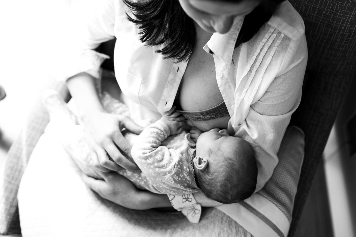 Gustavo Sousa estúdio de fotografia em Maringá-PR. Ensaio e book fotográfico newborn lifestyle e família. Foto em preto e branco, mãe  amamentando bebê vista de cima.