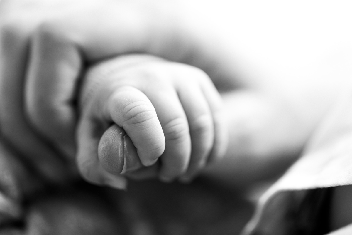 Gustavo Sousa estúdio de fotografia em Maringá-PR. Ensaio e book fotográfico newborn lifestyle e família. Foto em preto e branco da mãozinha do bebê segurando o dedo da mãe.