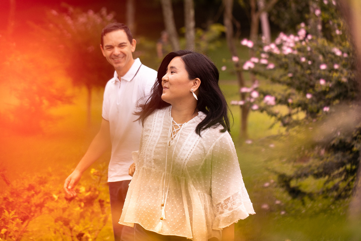 Gustavo Sousa estúdio de fotografia em Maringá-PR. Ensaio e book fotográfico gestante. Foto de grávida a frente e pai ao fundo sorrindo.