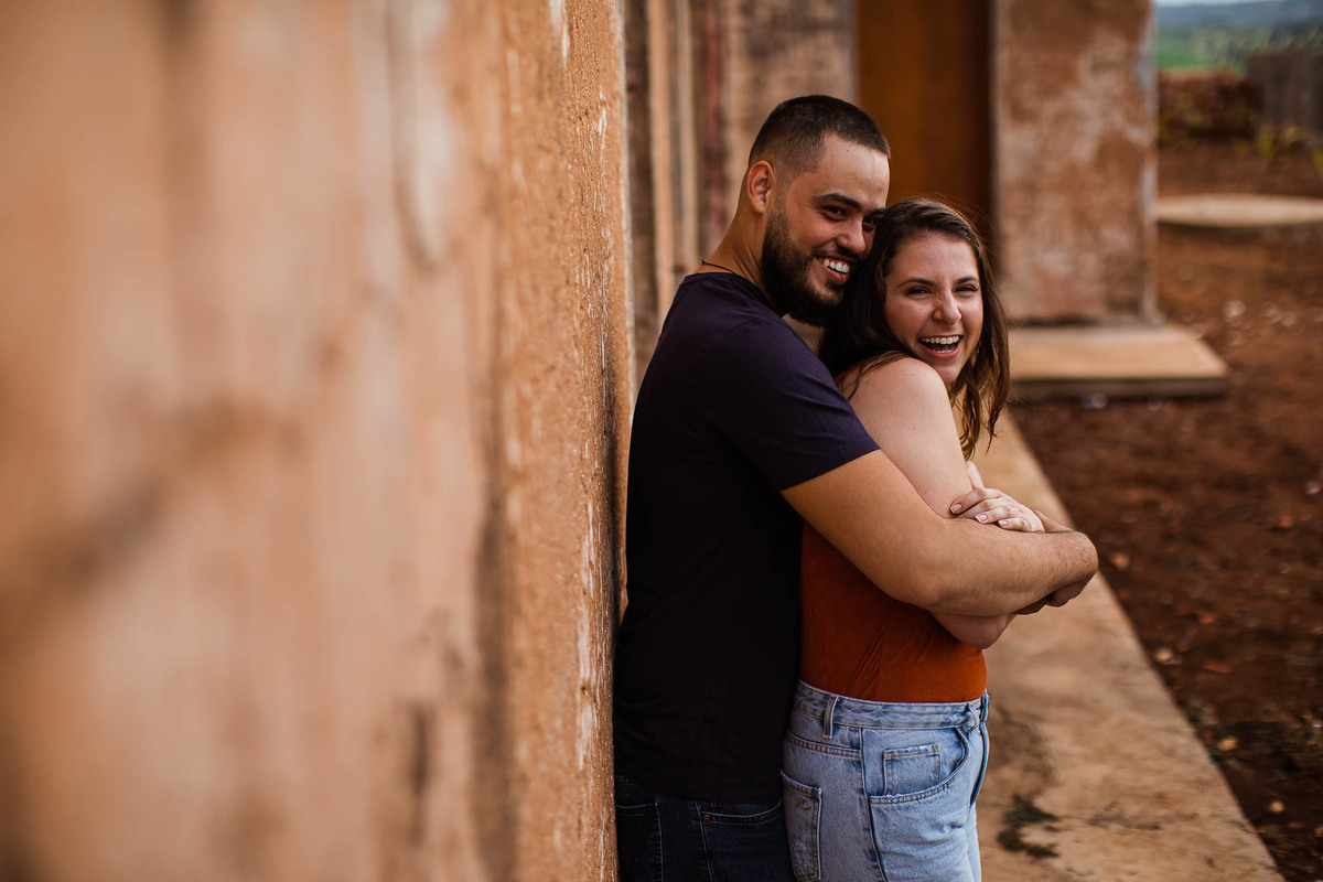 Capela Sagrada Família - Ruínas - em Mandaguari, região de Maringá. Casal vestidos de preto em frente a porta da igreja. Foto por Gustavo Sousa Fotografia. Casal de abraçando na igreja