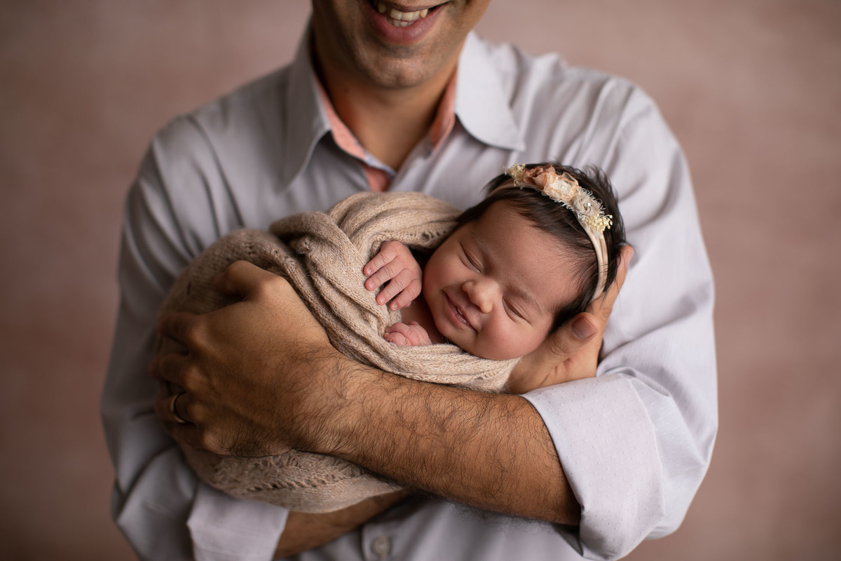 gustavo sousa fotografia em maringá estúdio de newborn e recém-nascidos. Fundo fotográfico rosa. Papai segunrando bebê recém nascido.