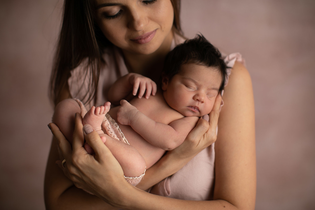 gustavo sousa fotografia em maringá estúdio de newborn e recém-nascidos. Fundo fotográfico rosa. Mamãe segurando recém-nascido.