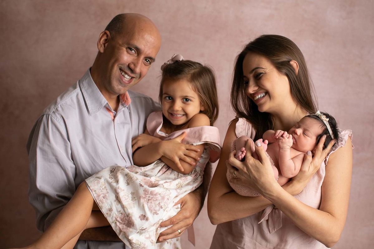gustavo sousa fotografia em maringá estúdio de newborn e recém-nascidos. Fundo fotográfico rosa. Família feliz com recém-nascido.