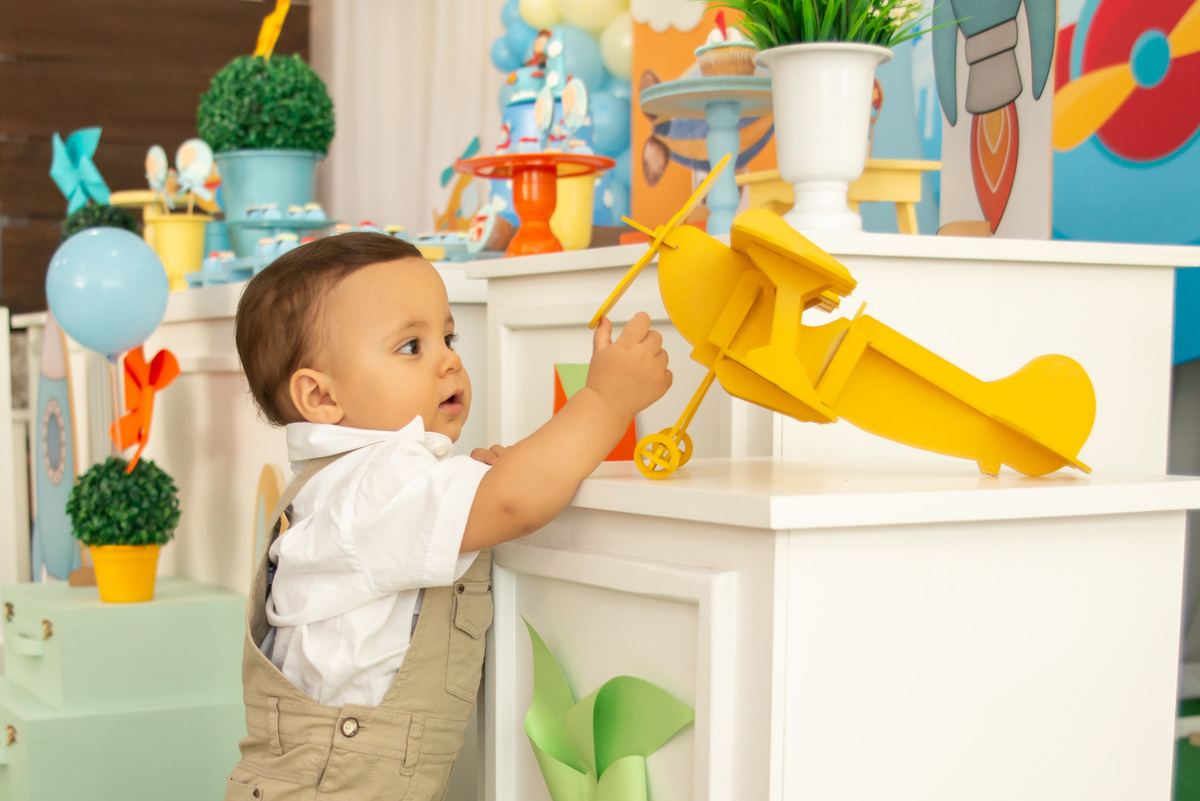 Decoração Urso Aviador, menino de um ano brincando com aviãozinho