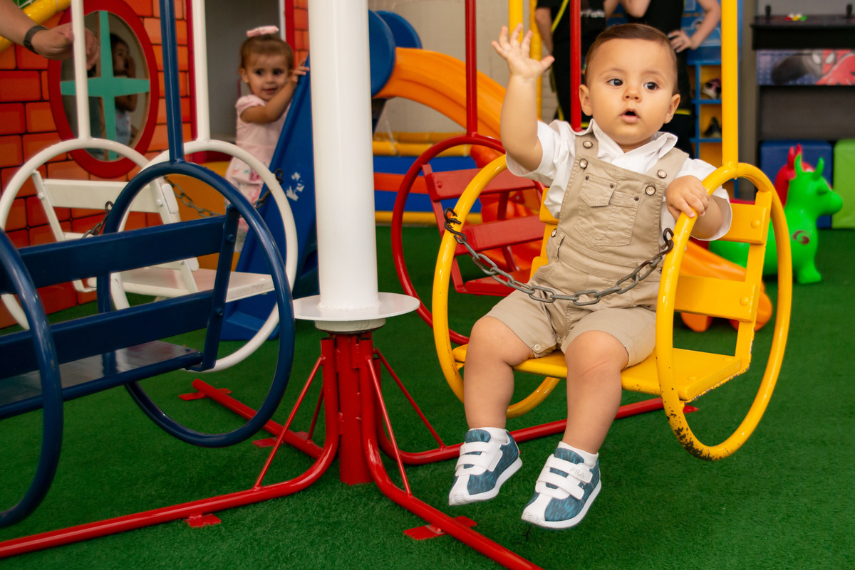 menino de um ano em brinquedo de balanço em festa de casa infantil