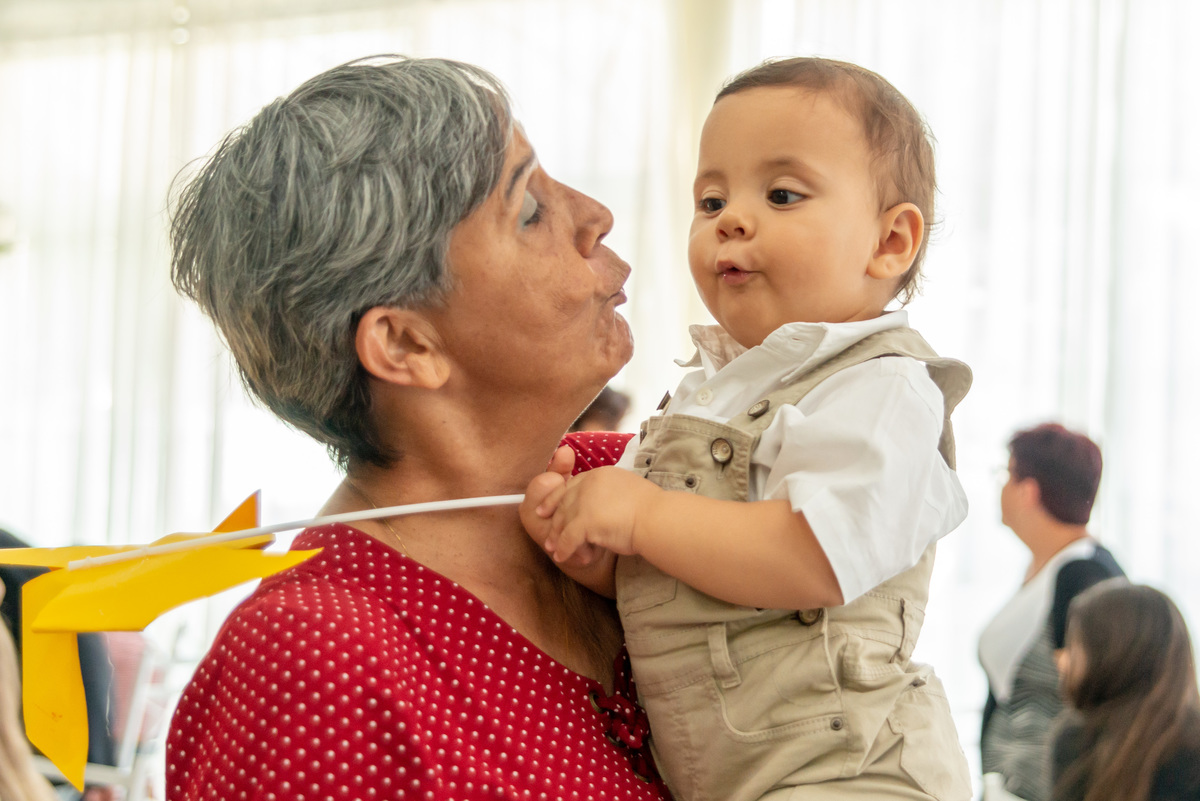 menino de um ano fazendo biquinho no colo da vovó