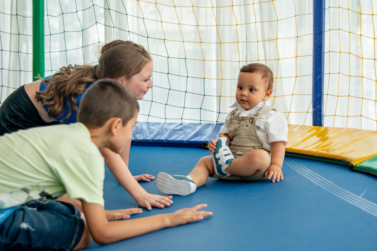 menino de um ano brincando em cama elástica com mais crianças