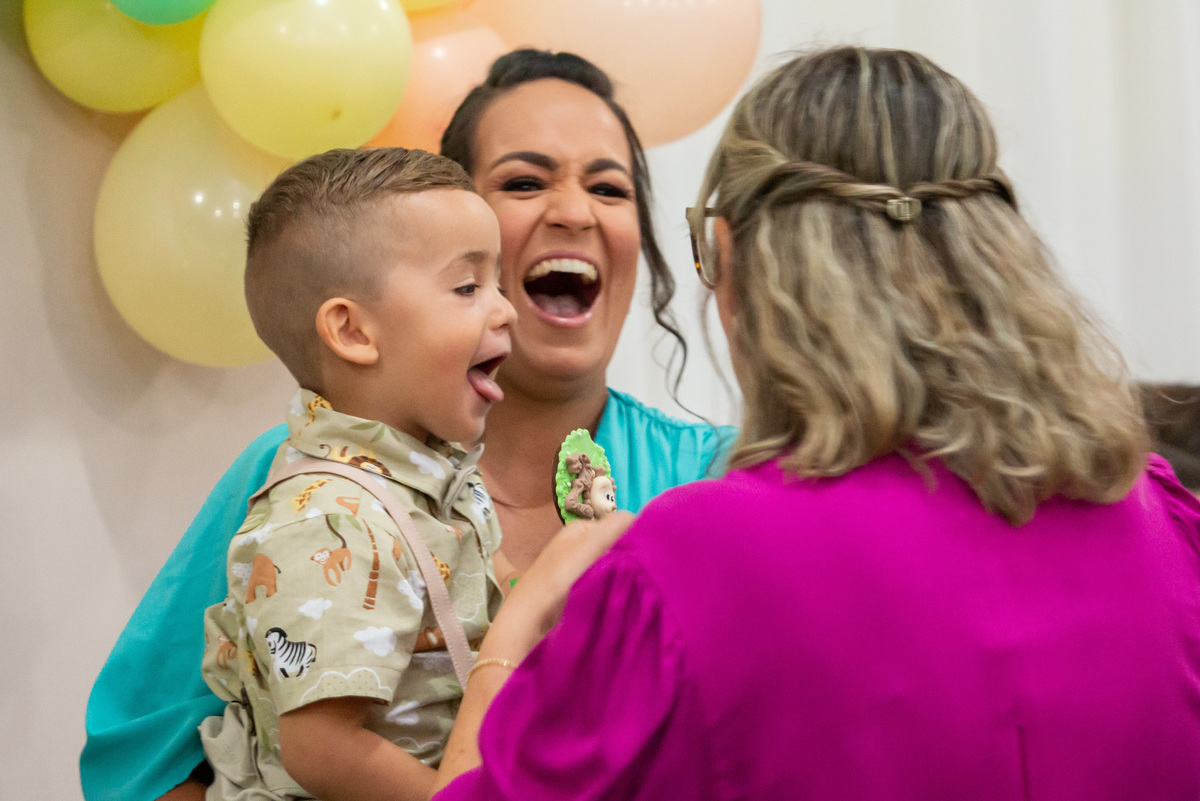 Menino de 2 anos no colo da mãe feliz comendo pirulito de chocolate
