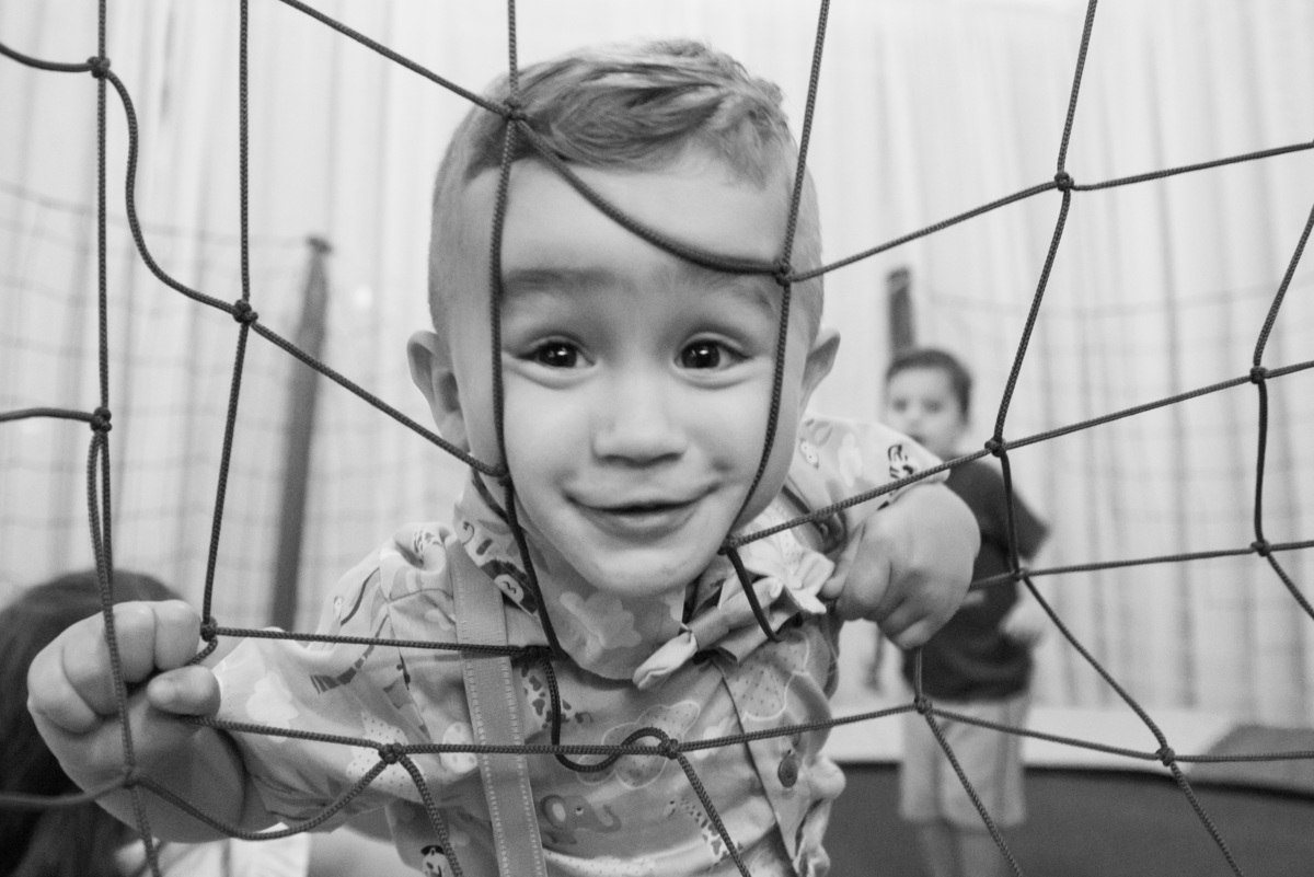 menino de 2 anos espiando por rede de cama elástica