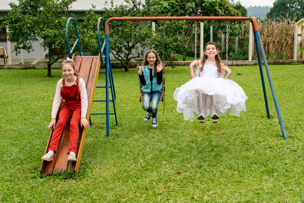amigas brincando no balanço e escorregador - vestido de primeira comunhão