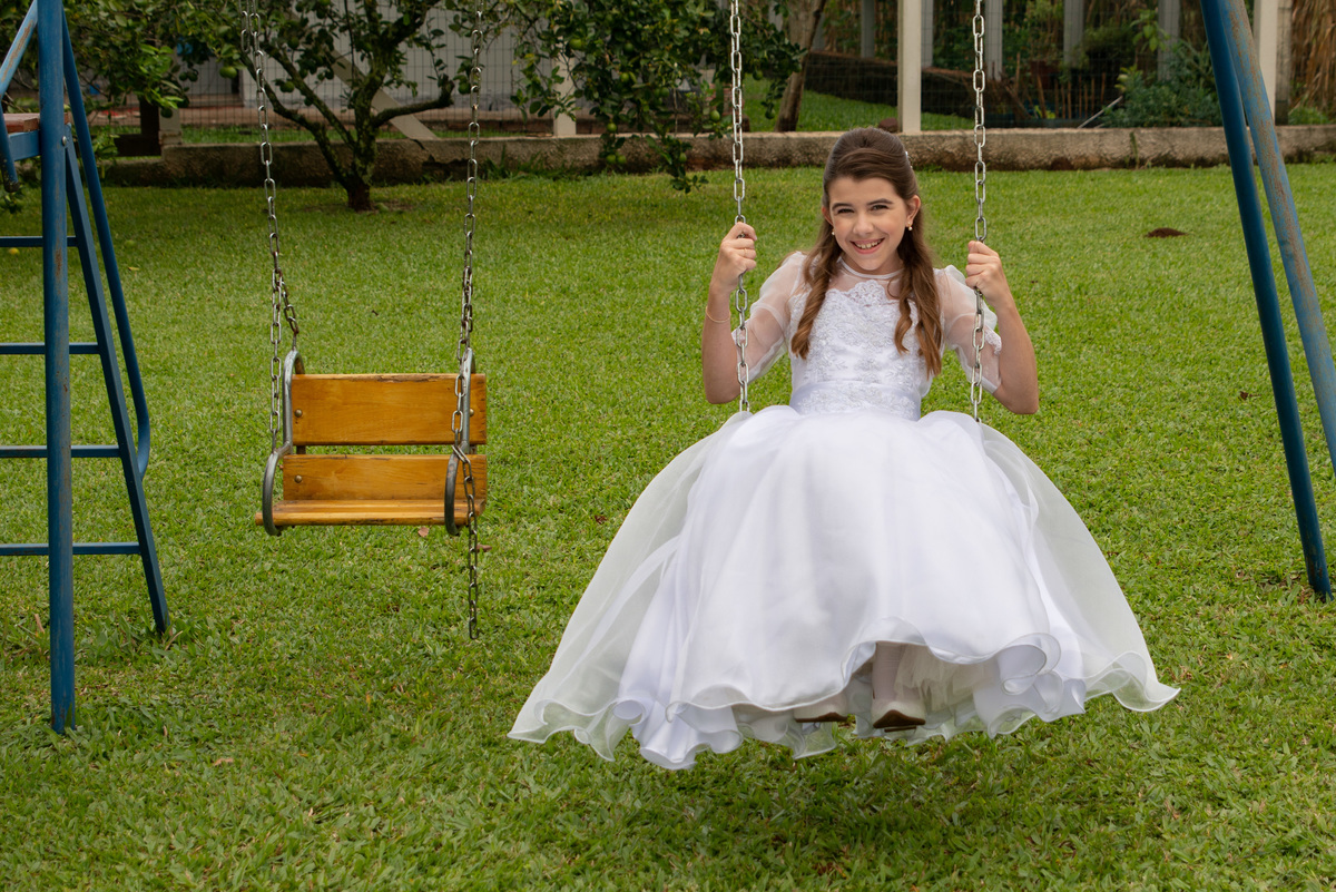 menina com vestido de primeira comunhão no balanço