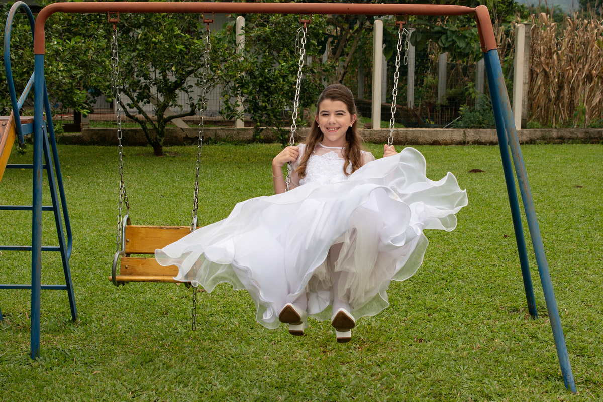 menina com vestido de primeira comunhão no balanço
