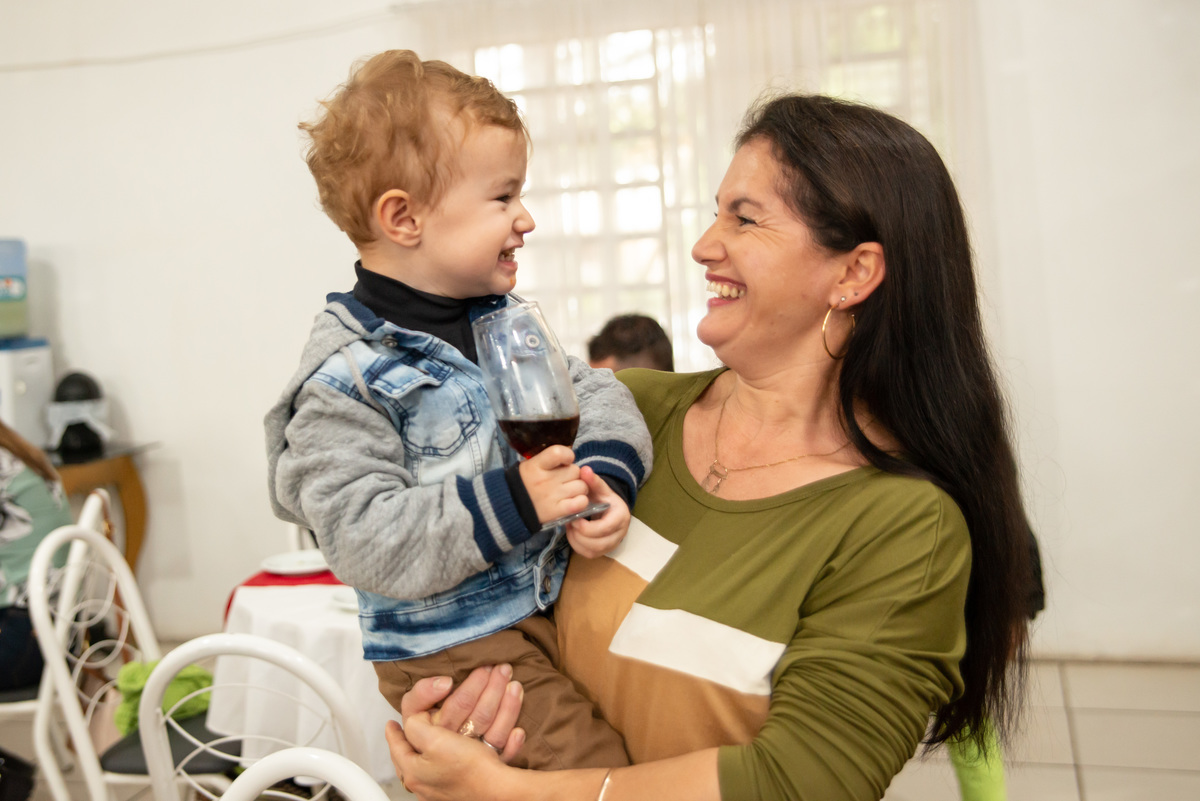 criança feliz no colo da mãe em festa infantil