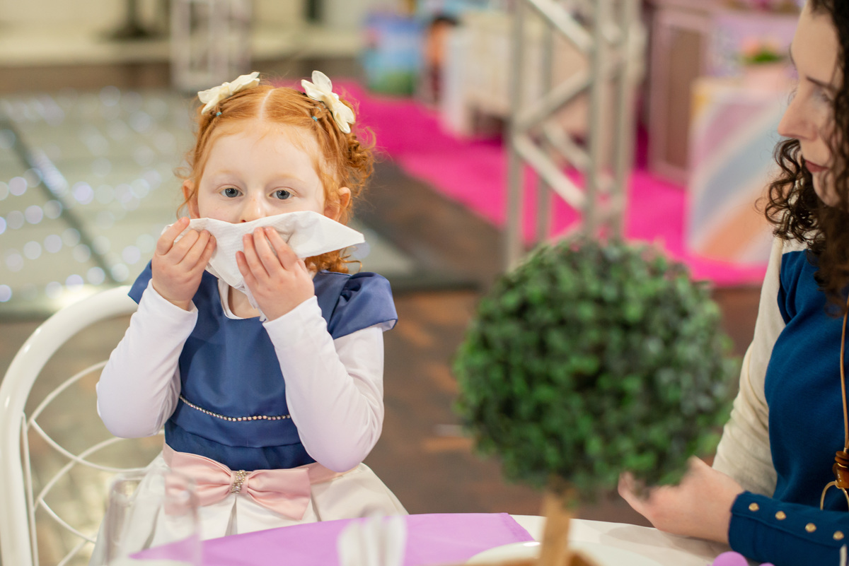menina ruiva de 3 anos em sua festa de aniversário infantil limpando a boca com guardanapo