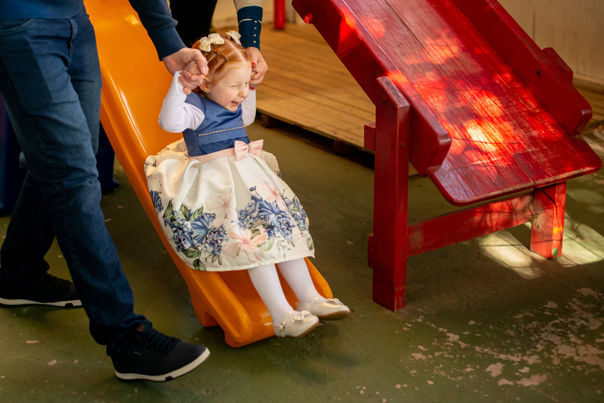 menina ruiva de 3 anos em sua festa de aniversário infantil brincando em escorregador