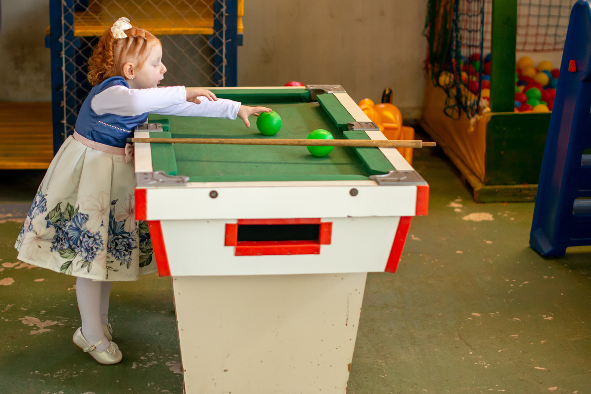 menina ruiva de 3 anos em sua festa de aniversário infantil brincando em mesa de sinuca