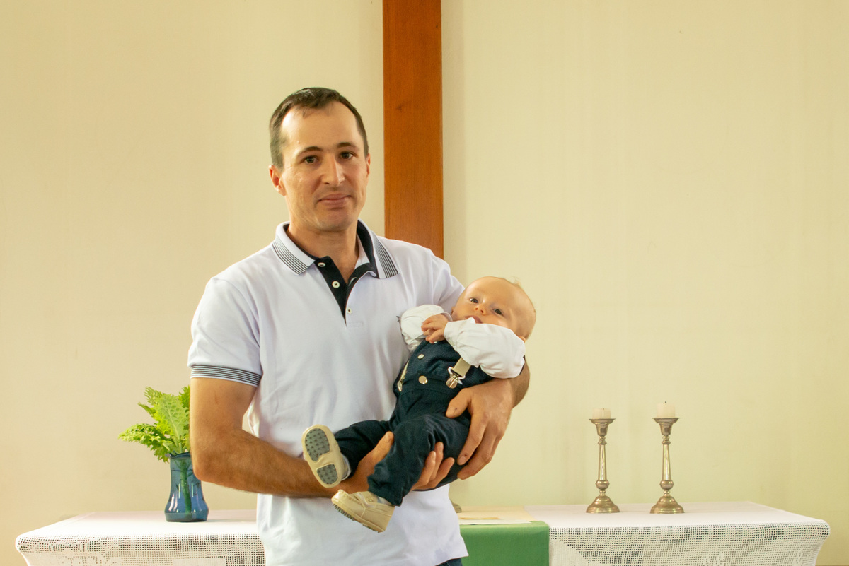 Bebê em seu batizado com o padrinho no altar da igreja - IECLB