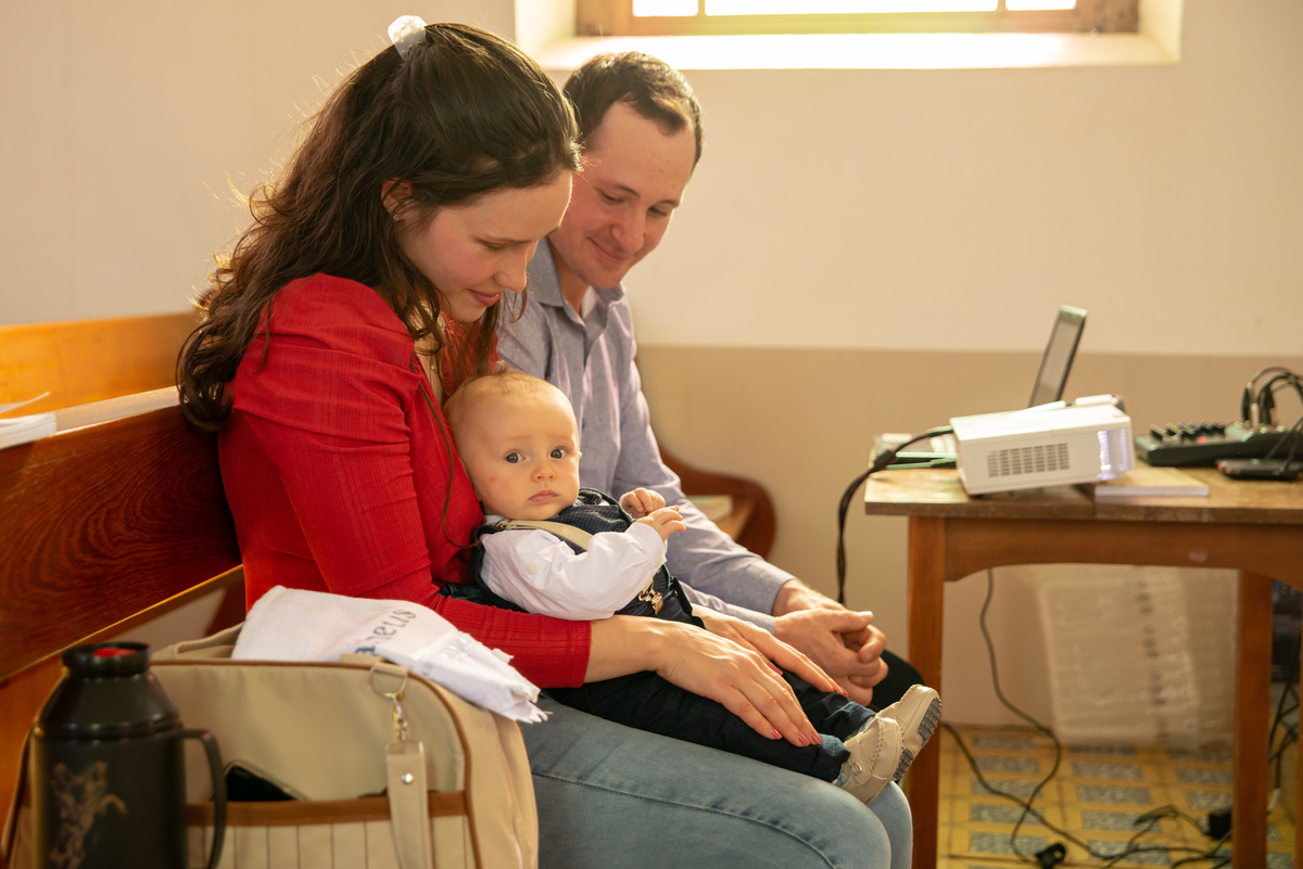 bebê no colo da mãe em banco da igreja - IECLB