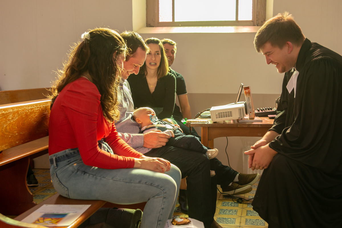 bebê dormindo no colo dos pais em banco de igreja - IECLB