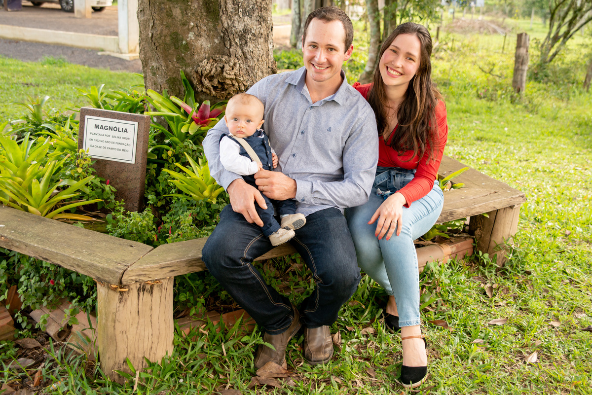 papais e bebê em foto externa após o batizado