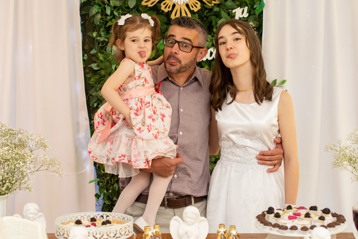 pai e filhas com a língua de fora em foto na festa de primeira comunhão