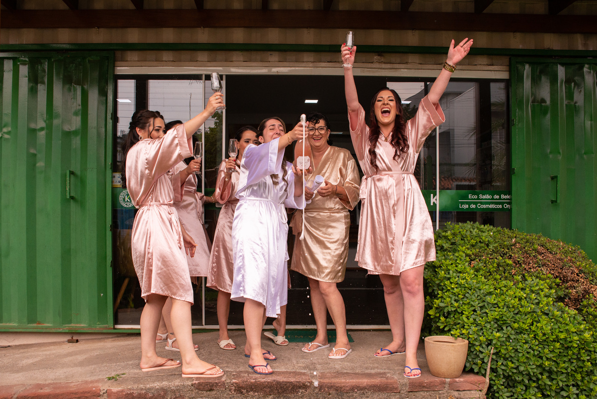 noiva, mãe e madrinhas comemorando com espumante no salão de beleza