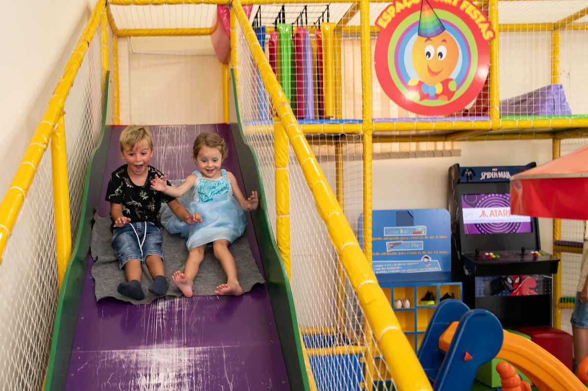 festa de aniversário infantil - aniversariante vestida de Elza Frozen com amigo descendo no escorregador