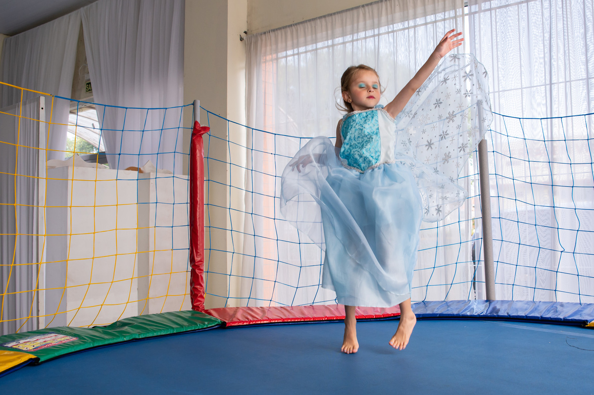 festa de aniversário infantil - aniversariante vestida de Elza - Frozen pulando na cama elástica